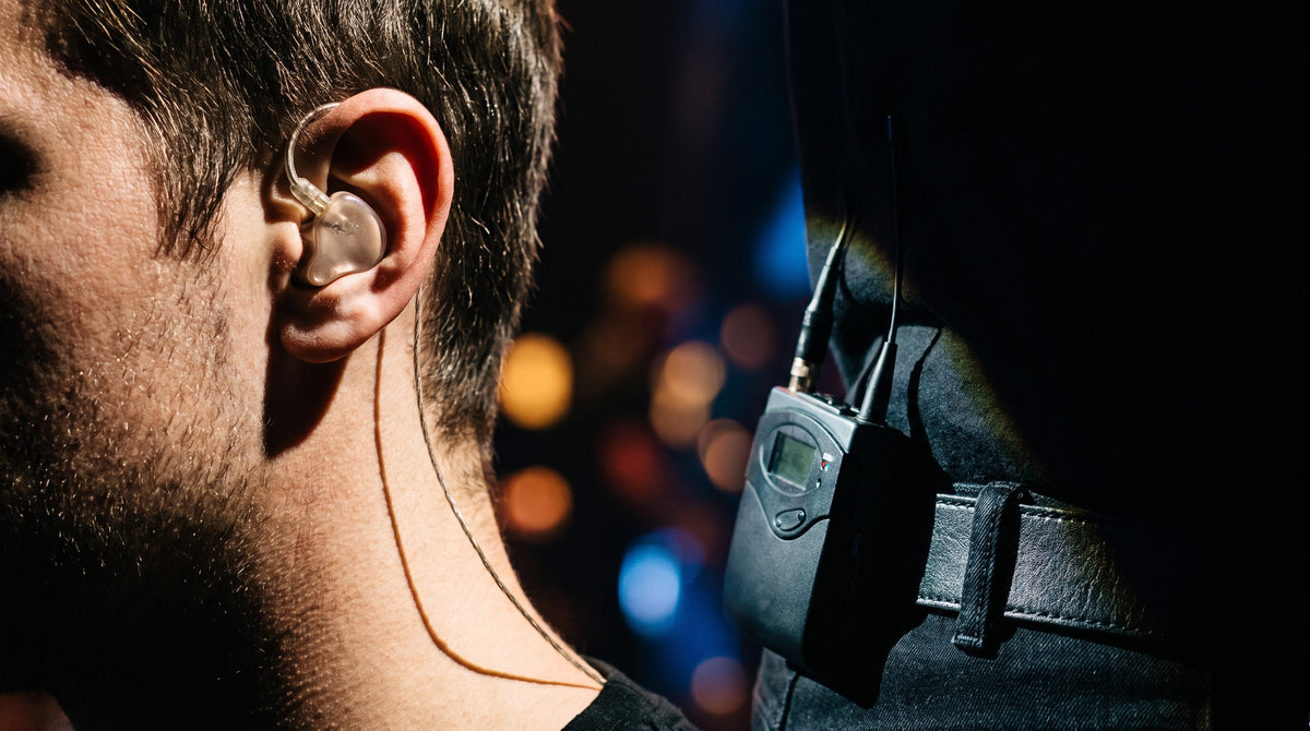 Musician wearing a wireless in-ear monitor system on stage